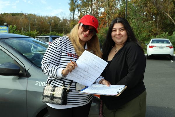 Dari driving instructor assisting student with paperwork at 2020 Driving School